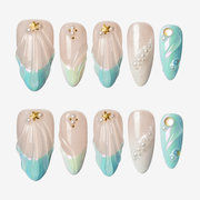 Flat lay of mermaid shell almond press-on nails with 3D shell texture and pearl accents in mint ombre.